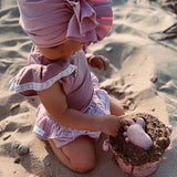 Scrunch Sand Moulds - Old Rose (Footprints Set) lifestyle shot of child and bucket kneeling on sand