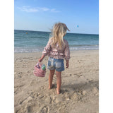 Life style shot girl on beach back view, carrying scrunch bag and items