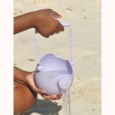 Scrunch Bucket - Pale Lavender, at beach pouring water, hands visible 
