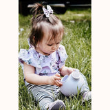 Pale lavender scrunch watering can, with young sitting child 